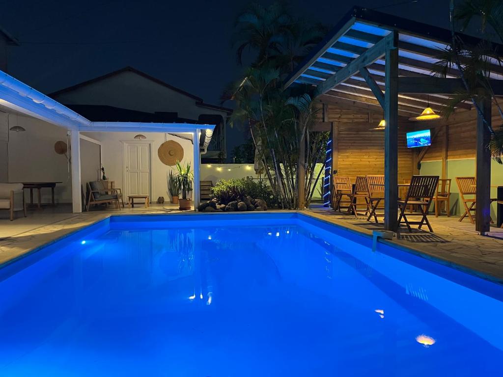 a swimming pool with blue lighting in a backyard at night at Coco Banana in Baie-Mahault