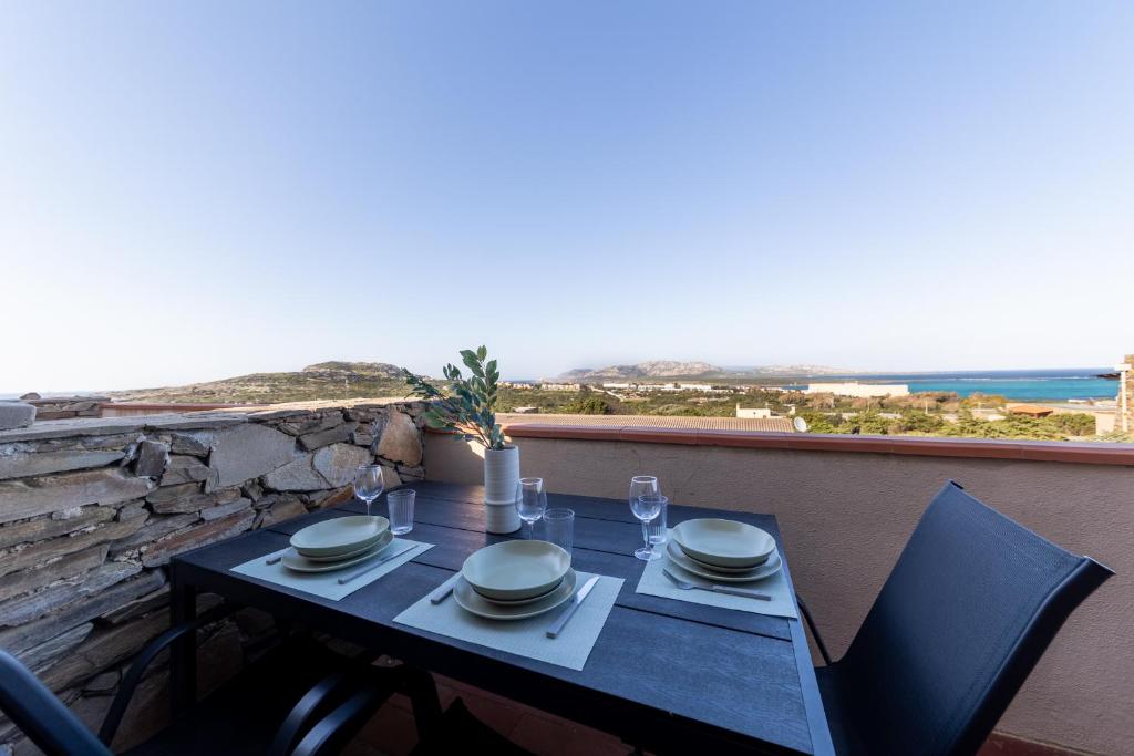 a table with plates and glasses on a balcony at L14 Appartamento Valle della Luna in Stintino