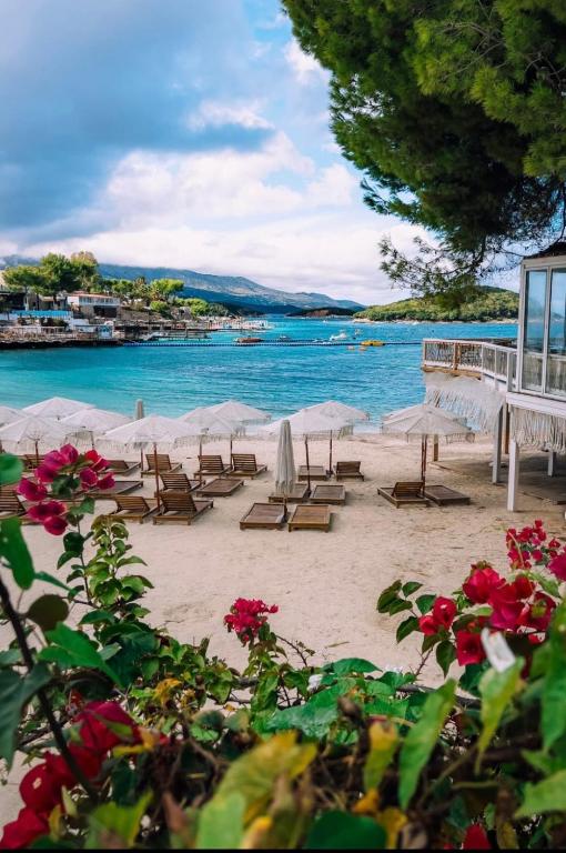 a beach with chairs and umbrellas and the water at Cozy Apartments Downtown in Ksamil