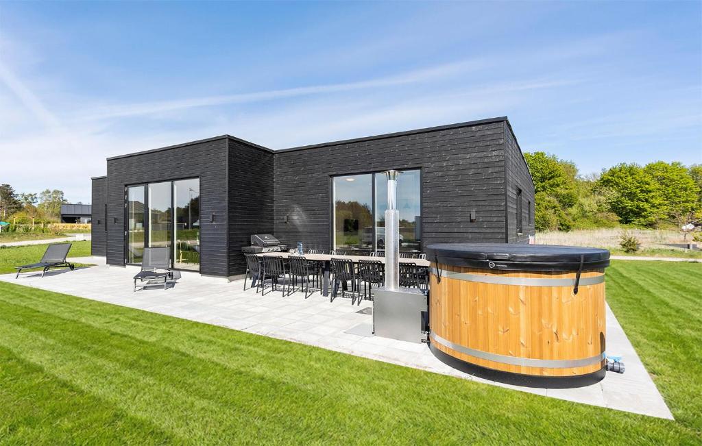 a black house with a wooden barrel in the yard at Awesome Home In Grenaa With Sauna in Grenå