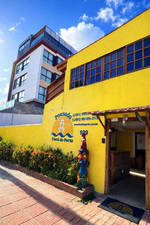 a yellow building with a sign on the side of it at Pousada Farol do Porto Nova ADM 2026 in Porto De Galinhas
