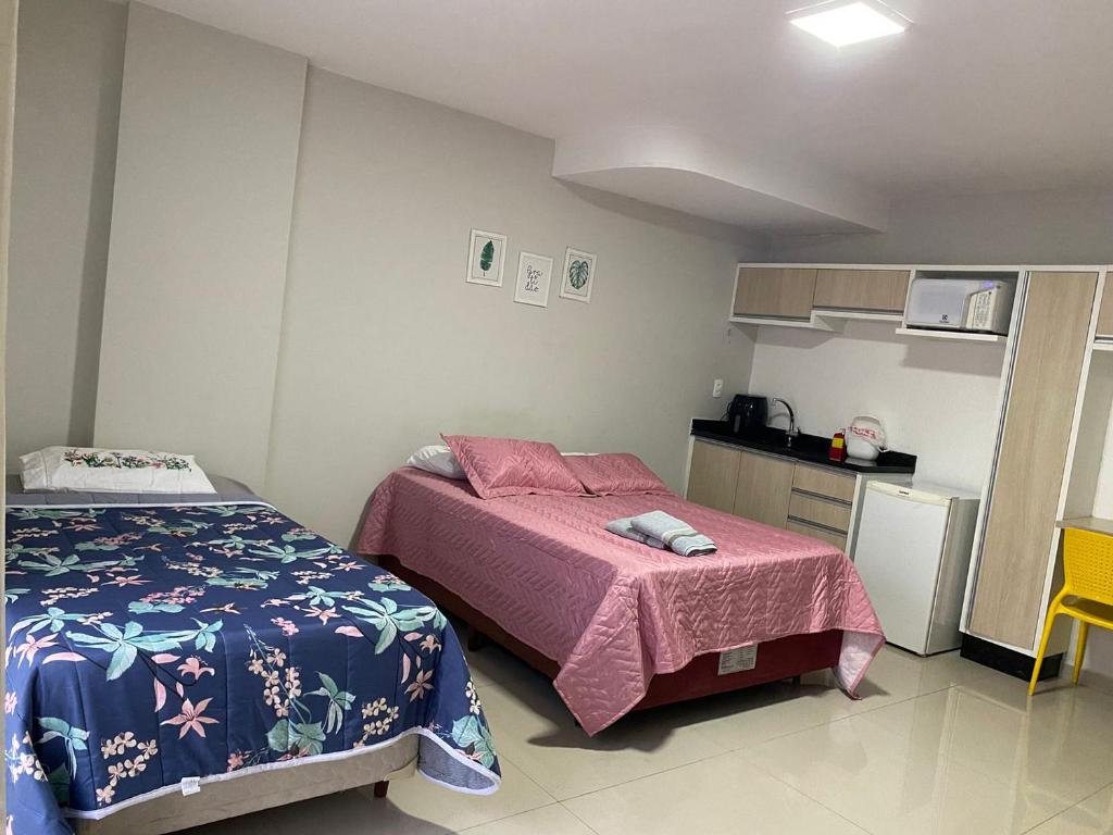 a small bedroom with two beds and a kitchen at 101 - Saint Sebastian Flat in Jaraguá do Sul