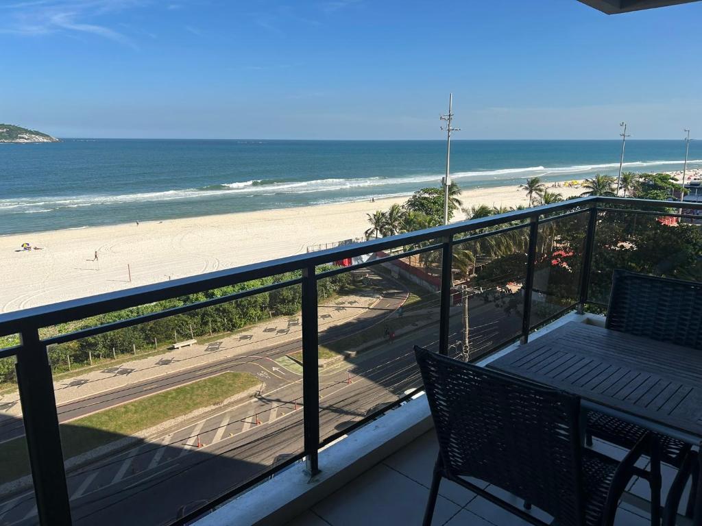 a balcony with a table and chairs and the beach at Beach Front 2 Bed Rooms - Balcony with Full Sea View - Praia do Pepê in Rio de Janeiro