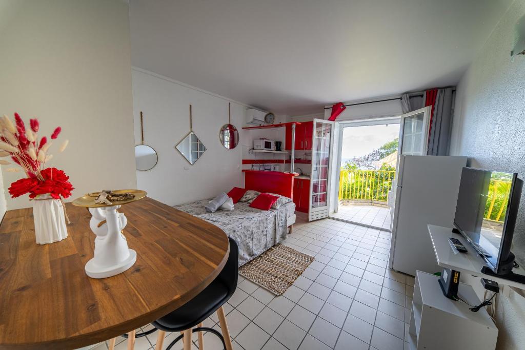 a living room with a table and a room with a bed at Beau studio au coeur du Gosier in Le Gosier