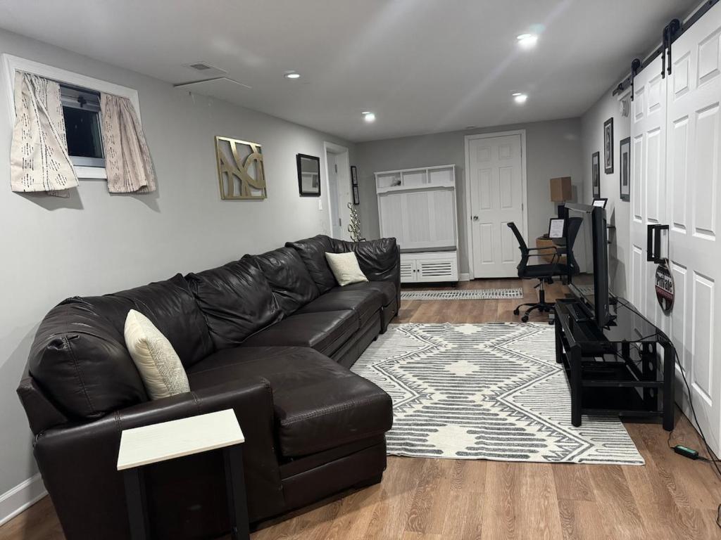 a living room with a black leather couch at 2BR Spacious Escape Close to DC & Baltimore in Laurel