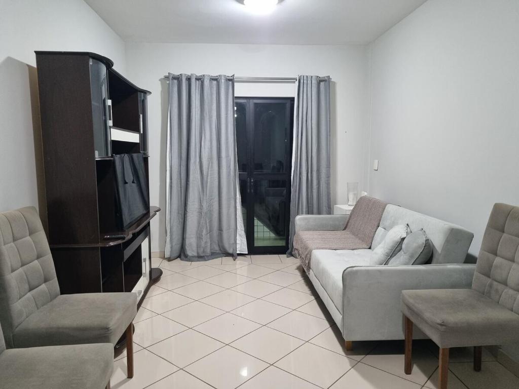 a living room with a couch and a tv at 2-bedroom apartment in Ubá