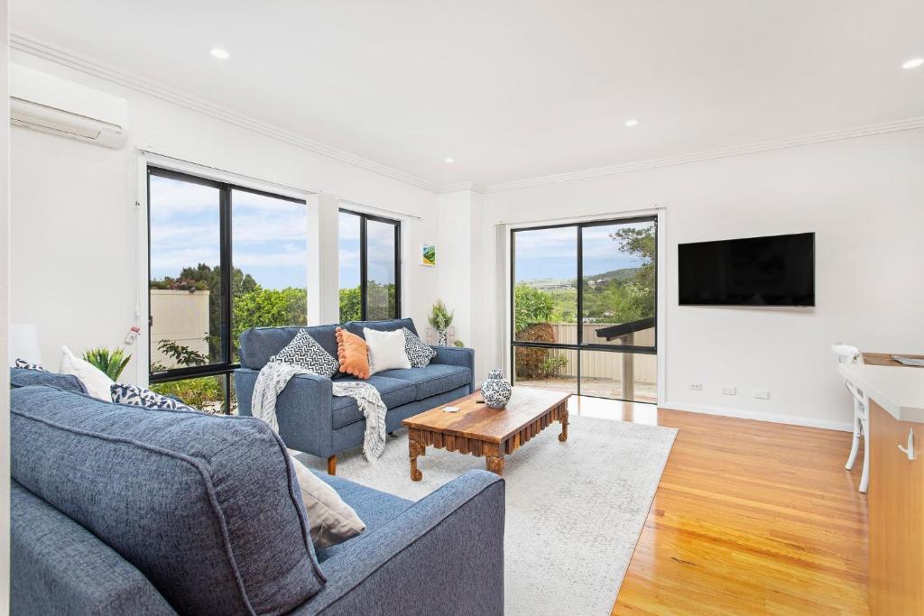 a living room with two blue couches and a tv at Echo Waves in Kiama