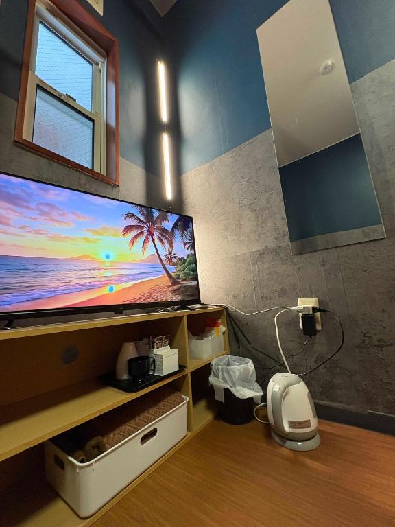 a room with a flat screen tv on a wall at fishing inn beach house in Amami