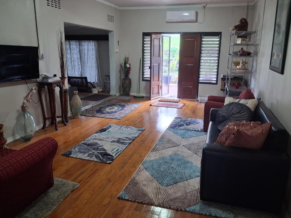 a living room with two couches and a wooden floor at Apianas BnB in Suva