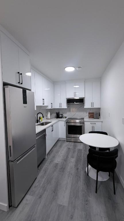 a kitchen with a refrigerator and a table in it at Private Creekstone Basement Suite with Kitchen in Calgary