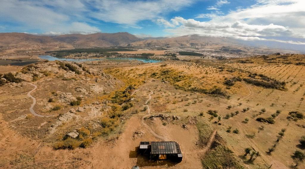 an aerial view of a hill with a river and mountains at Tāima PurePod in Cromwell
