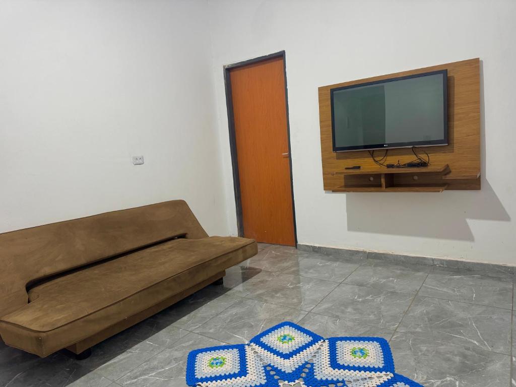 a living room with a couch and a flat screen tv at Casa Grande e Climatizada in Campo Grande
