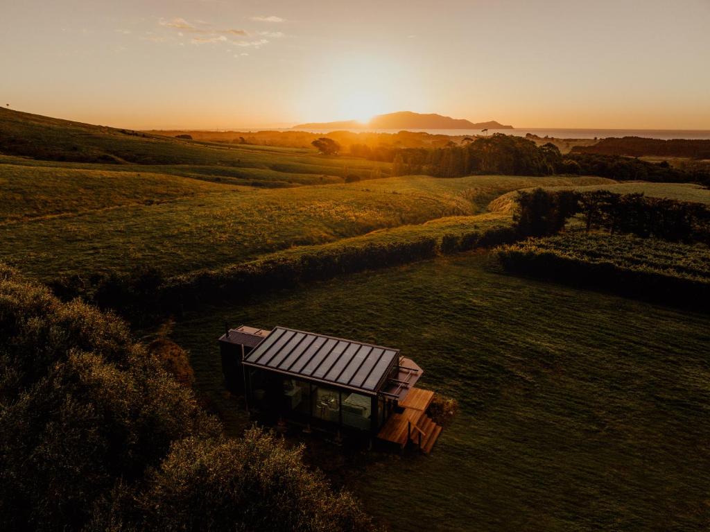 an aerial view of a field with the sun setting at Kokomea PurePod in Te Horo