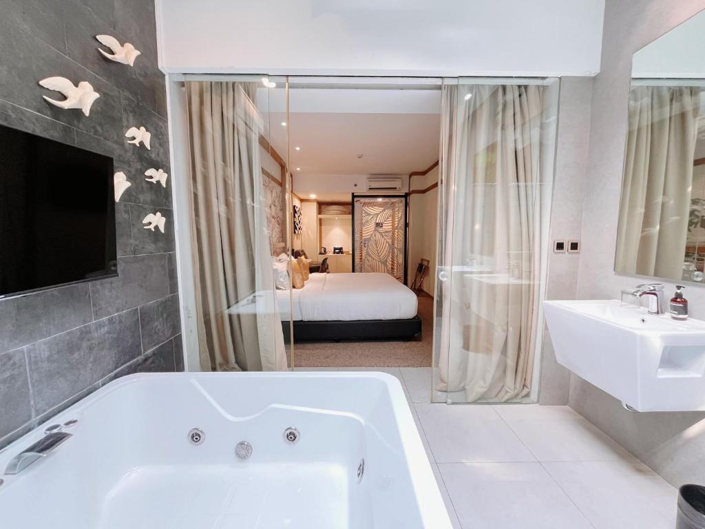 a bathroom with a tub and a sink and a bed at Verse Luxe Hotel Wahid Hasyim in Jakarta