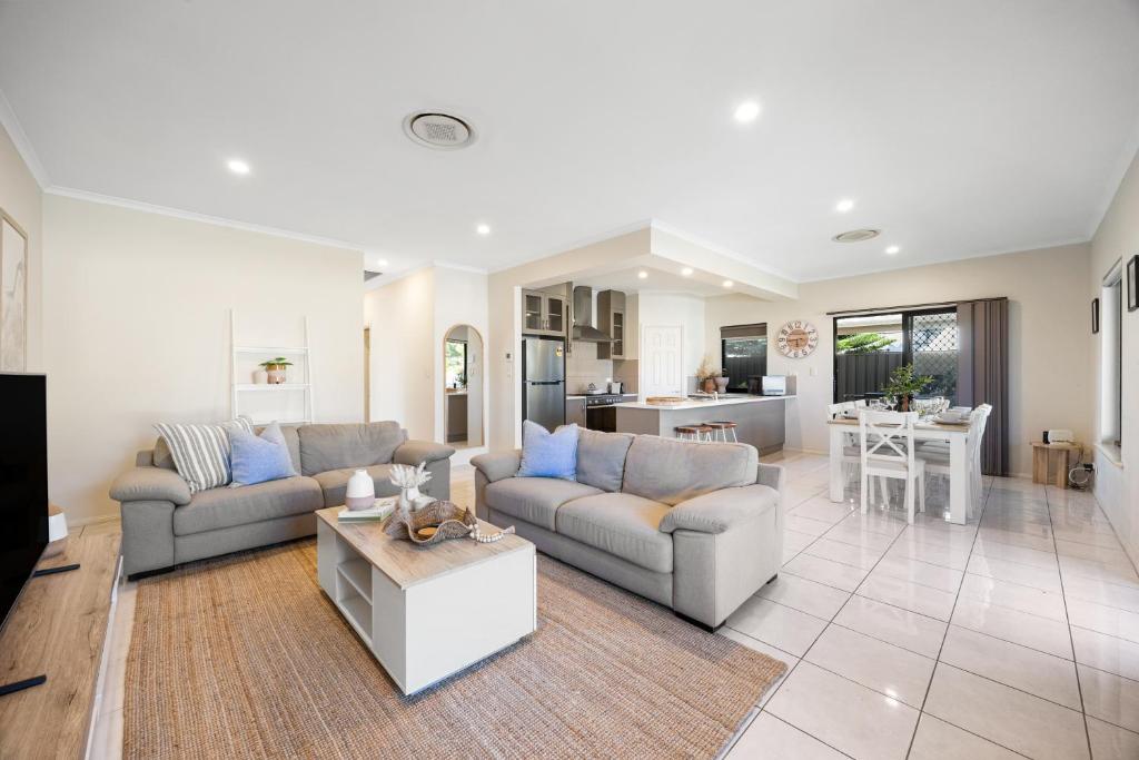 a living room with two couches and a kitchen at Gone Coastal - Family Beachside Breeze in Grange
