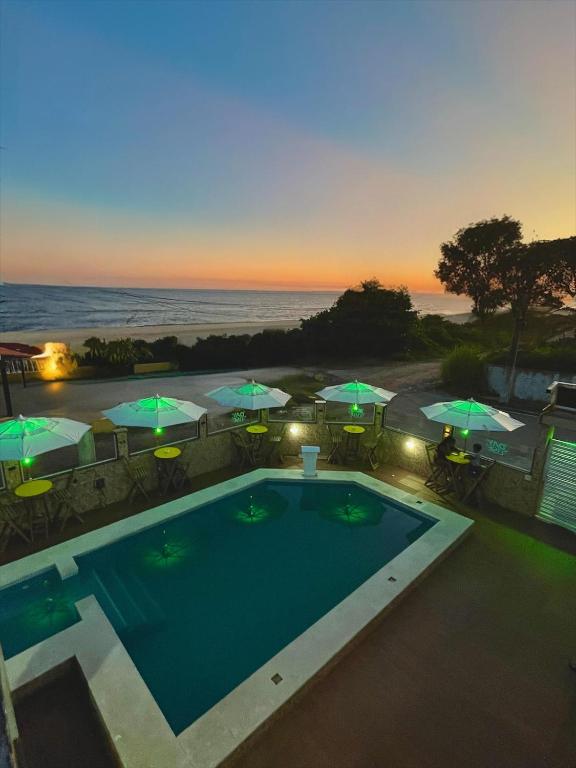 a view of a pool with umbrellas and the ocean at Pousada & Espaço Orlla 39 in Maricá