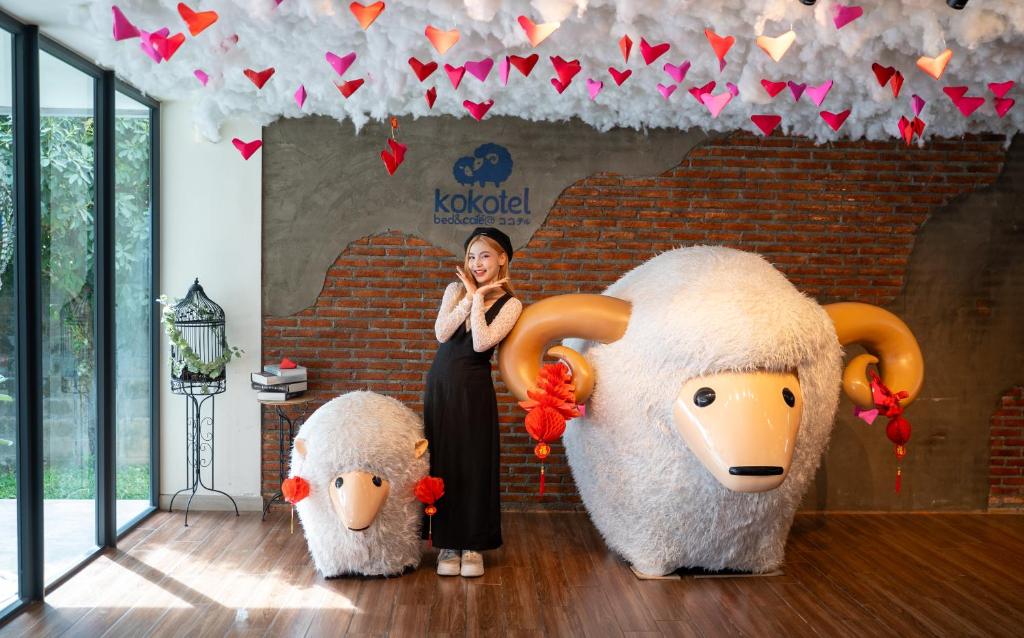A bright branded lobby corner staged with a guest and two decorated sheep figures.