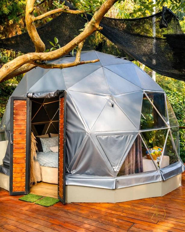a tent on a deck with a tree at Omghat Glamping - Domo Sarasvasti in El Peñol