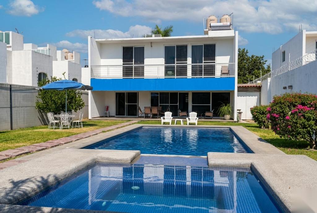 a villa with a swimming pool in front of a house at Home in Tequesquitengo in Tequesquitengo