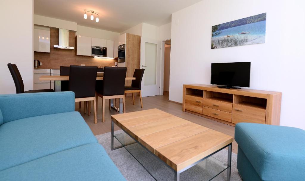 a living room with a blue couch and a television at Premium Apartments am Weißensee in Weissensee