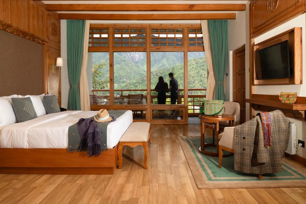 a bedroom with a bed and a balcony with people standing outside at Amba Paro in Paro