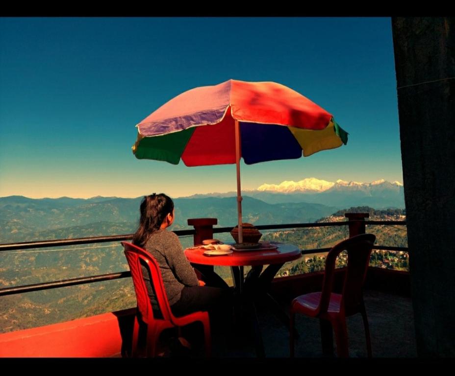 a woman sitting at a table with an umbrella at Homestay in Darjeeling By NE DEN in Jāmb