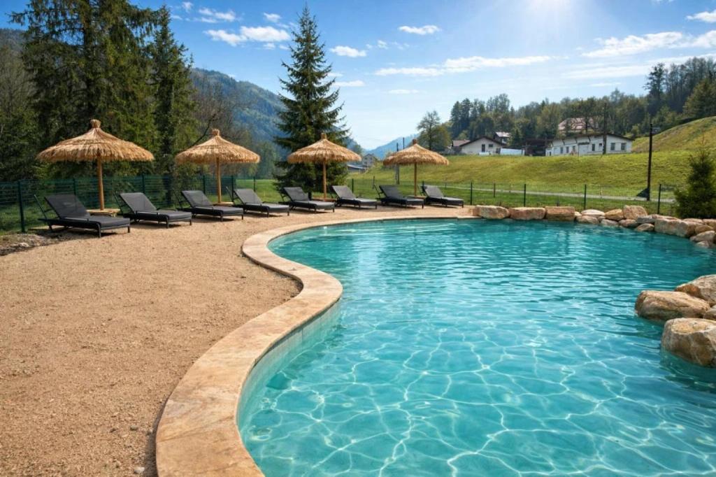 a swimming pool with chairs and umbrellas at Camping nature 3 étoiles avec piscine - bord de rivière in Chézery-Forens