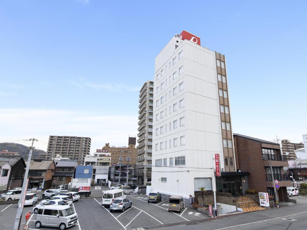 a white building with cars parked in a parking lot at Onomichi Daiichi Hotel in Onomichi