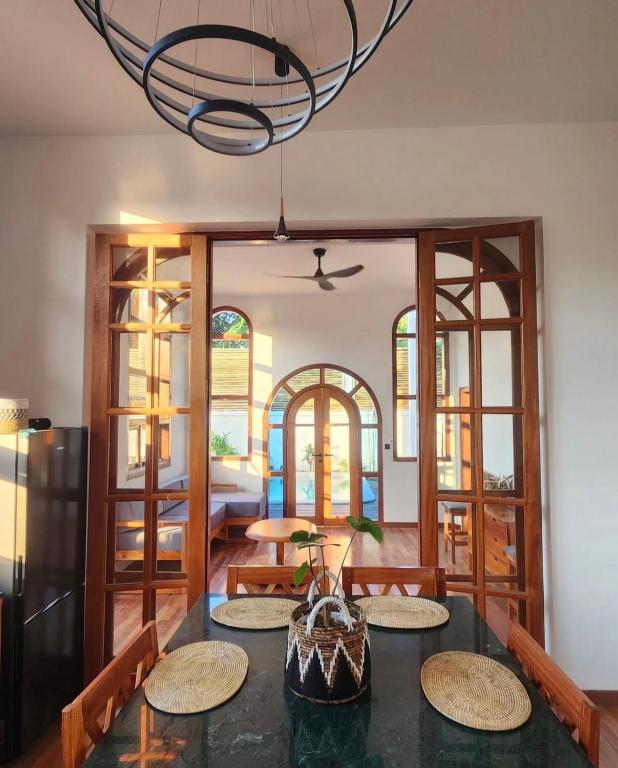 a dining room with a table and a chandelier at Markisa Villas - Spacious Private Pool Homes on Gili Air in Gili Islands