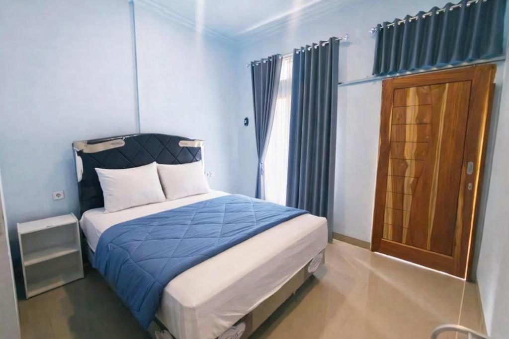 a bedroom with a bed with blue sheets and a window at Cherry Homestay in Kuta Lombok