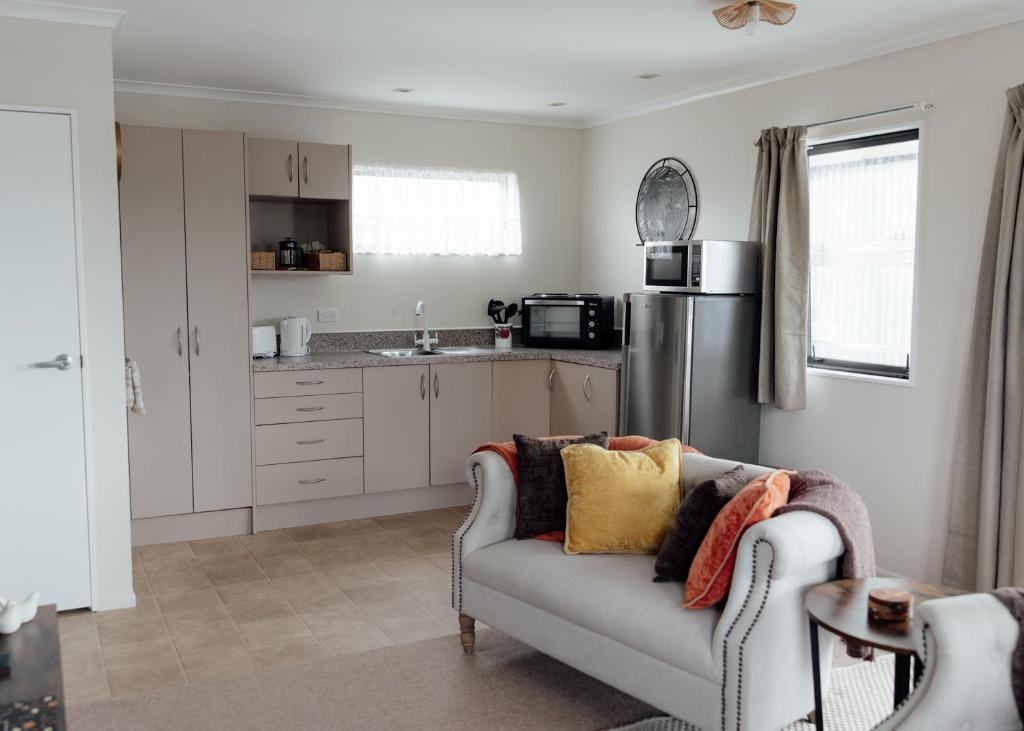 a living room with a couch and a kitchen at Pembroke View in Carterton