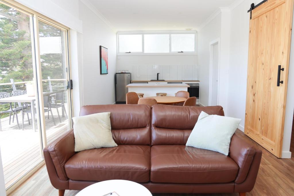 a living room with a brown leather couch and a table at Harbour View Motel in Robe