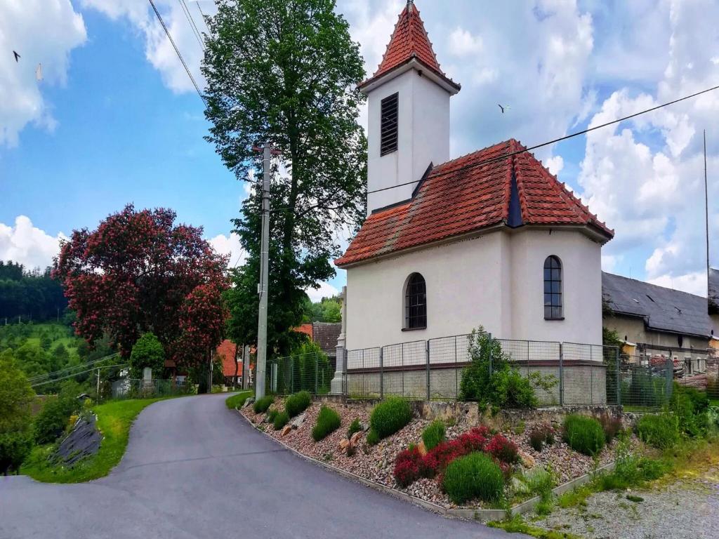 a small white church with a red roof at Villa in Býšovec near Harusak Ski Resort in Ujčov