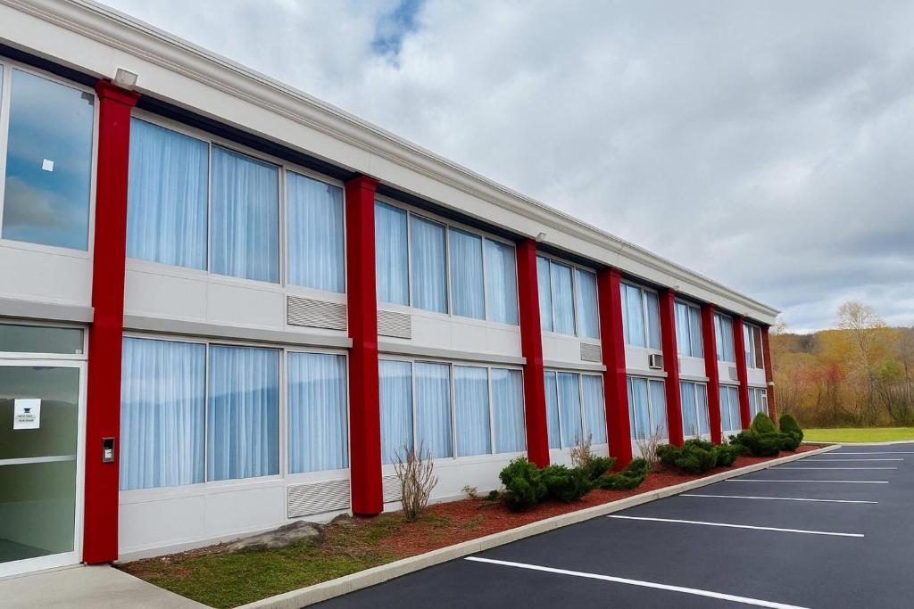 a large building with red columns in a parking lot at Ramada by Wyndham Cobleskill in Cobleskill