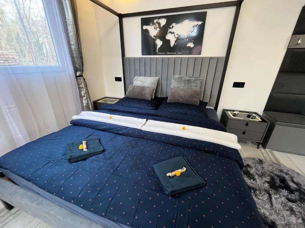 a bedroom with two beds with blue comforter at Csiszta Thermal Villa in Buzsák