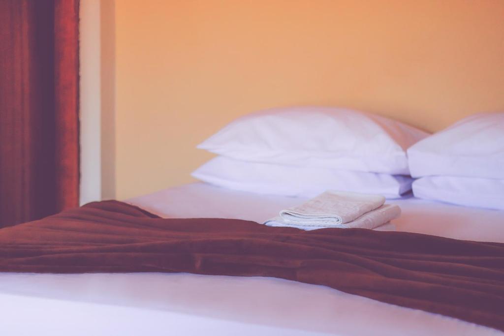 an unmade bed with white pillows at Vitória Hotel in Monte Alto
