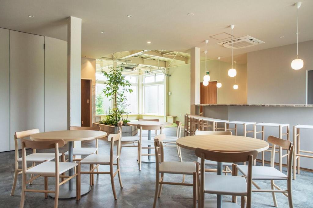 a restaurant with wooden tables and white chairs at 水の郷リトリート 再 in Katori