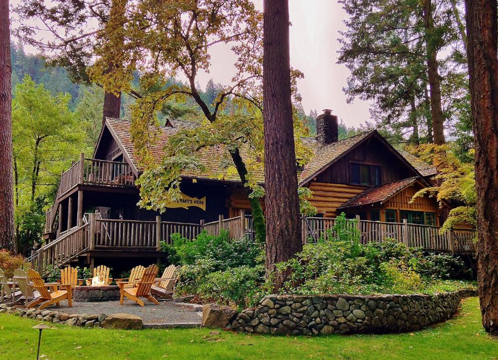 a log cabin in the woods with chairs and trees at Weasku Inn in Grants Pass