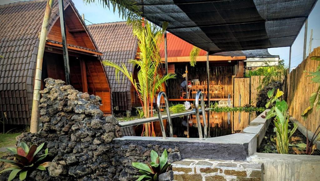 a house with a pond in front of it at Pondok Kayu Canggu in Dalung
