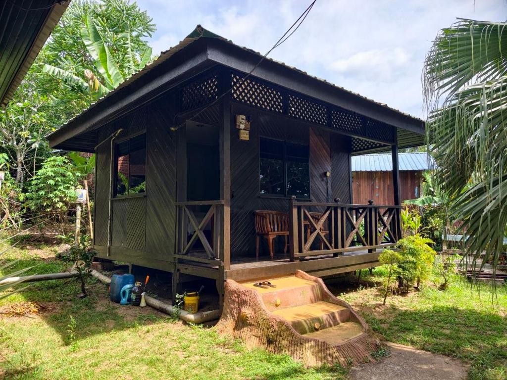 a small wooden house with a chair in the yard at Nazri's Place 2 in Tioman Island
