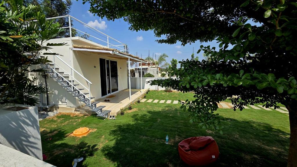 a house with a porch and a staircase next to a yard at Rewind by NestoraHomes in Jadgenhalli