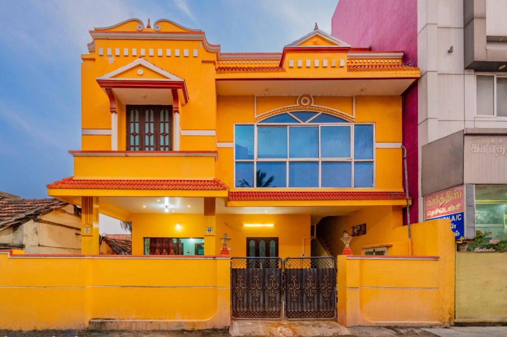 a yellow house in the middle of buildings at Karthees Homestay in Rāmeswaram