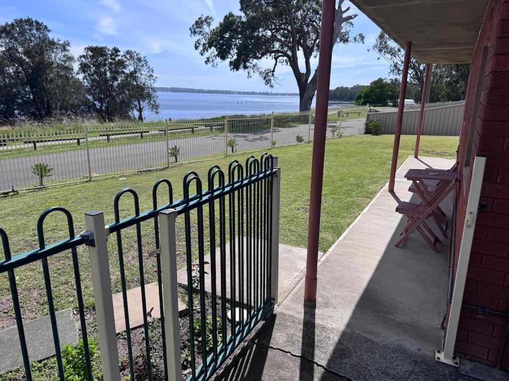 a fence on a porch with a view of the water at Toukley Lakeside Apartment in Toukley