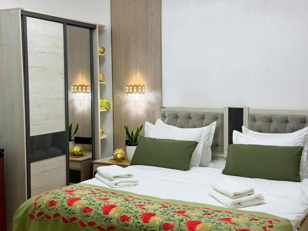 a bedroom with a large white bed with green pillows at Giza Grand Hotel in Tashkent