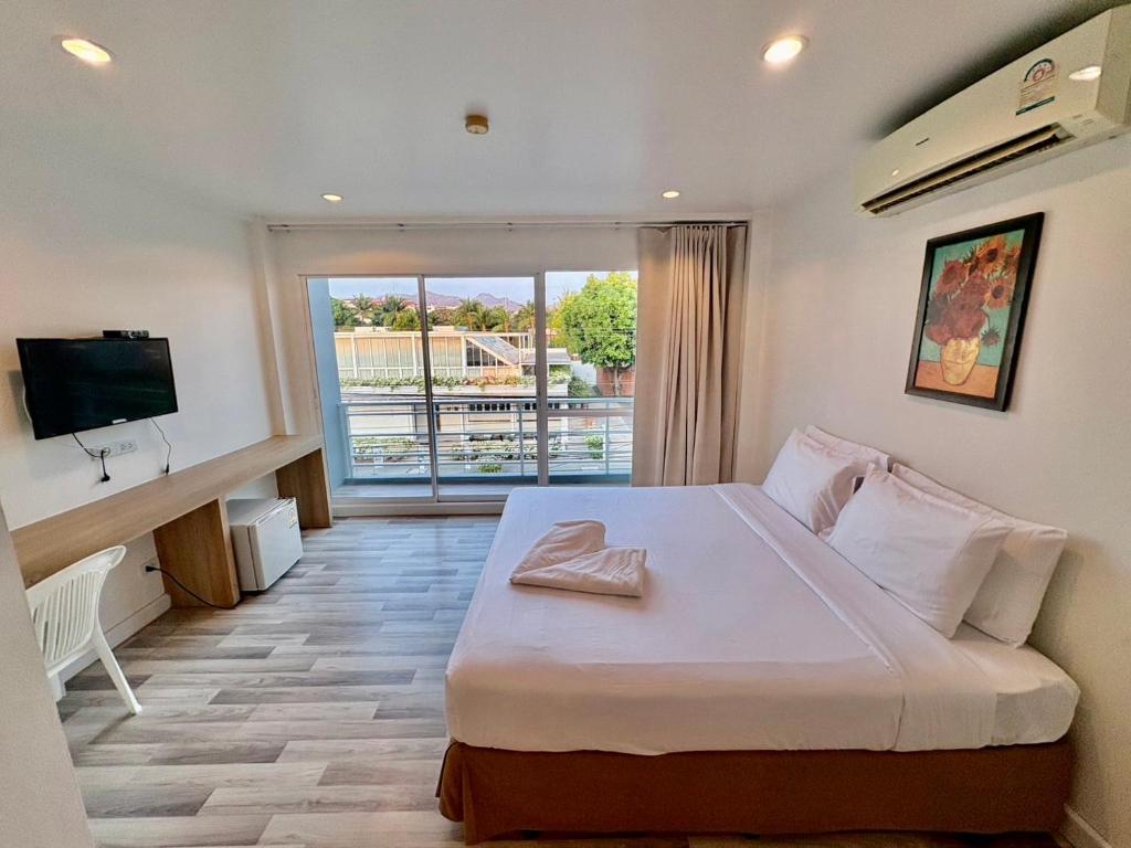 a bedroom with a large bed with a television and a balcony at Nantra Hua Hin in Hua Hin