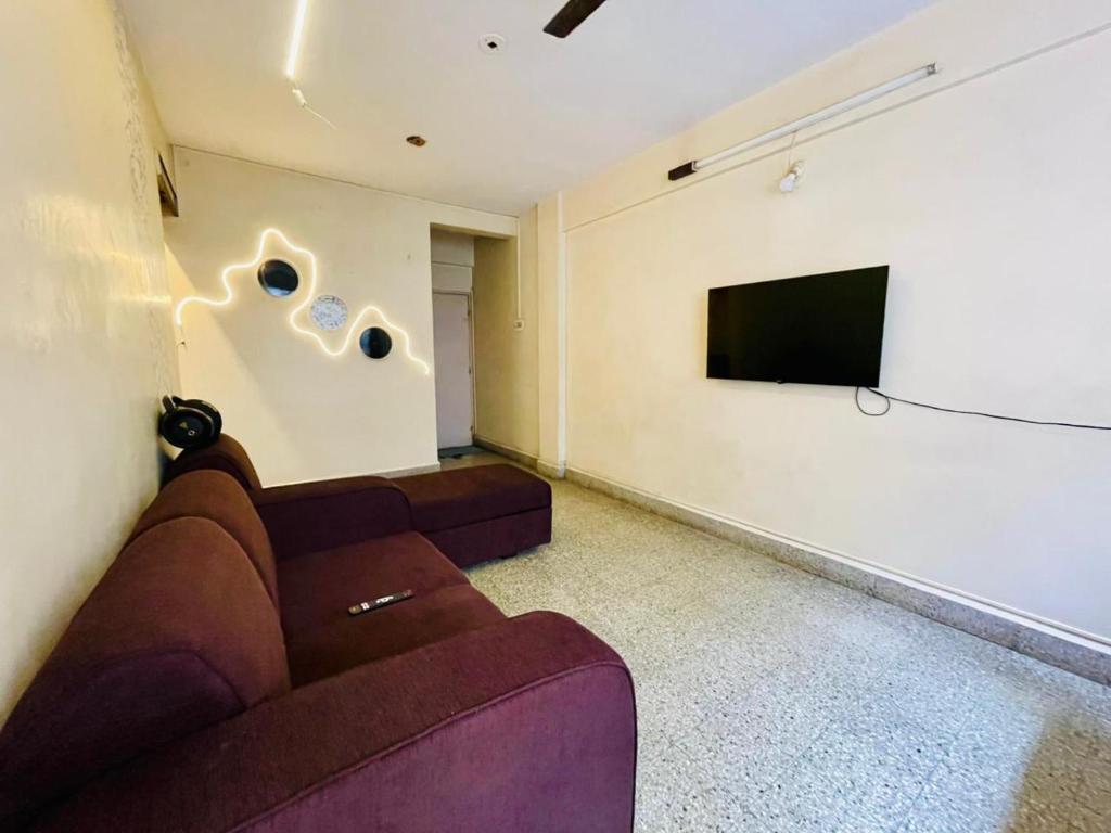 a living room with a couch and a flat screen tv at Flora 2bhk Kothrud MIT WPU in Pune
