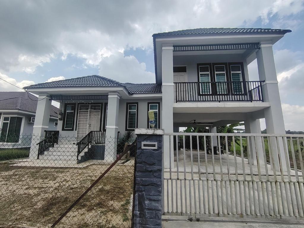 a house with a white fence in front of it at Miqayla Homestay in Wakaf Baharu