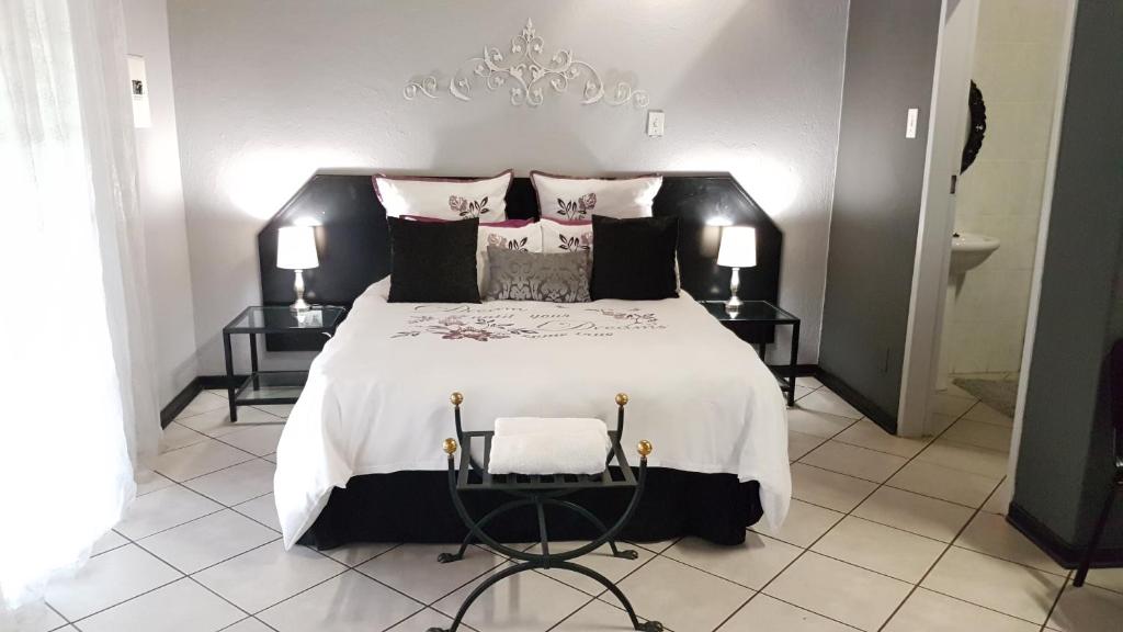 ein Schlafzimmer mit einem großen weißen Bett und einem Kronleuchter in der Unterkunft Siesta Guest House in Musina