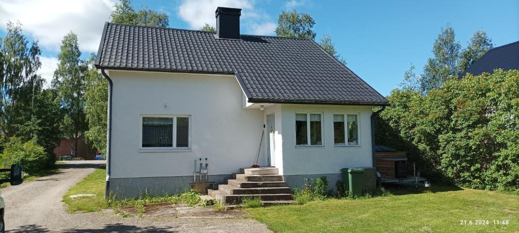a small white house with a black roof at Veteli in Veteli