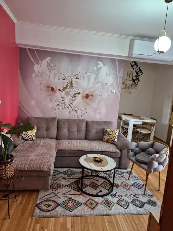 a living room with a couch and a wall with flowers at Fine Rest- Spacious & Cozy Apartment in Brčko